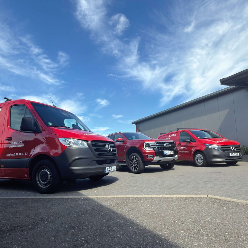 Drei neue Einsatzfahrzeuge von Clausen Haustechnik – zwei Mercedes Transporter und ein Ford Ranger – stehen auf dem Firmengelände vor blauem Himmel.