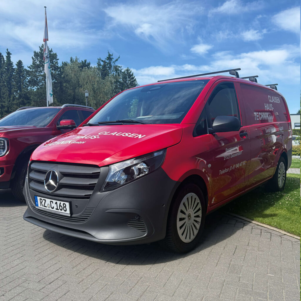 Ein roter Mercedes Transporter mit Firmenbeschriftung von Clausen Haustechnik steht auf dem Betriebsgelände. Im Hintergrund ist ein Ford Ranger zu sehen.